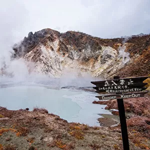 Danger sign in front of volcanic field and steaming pond in Noboribetsu, Hell Valley, Hokkaido, Japan, Asia