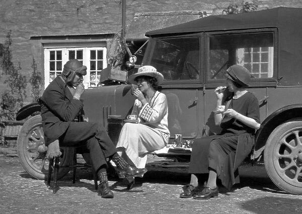 Three people picnicking at the side of a car