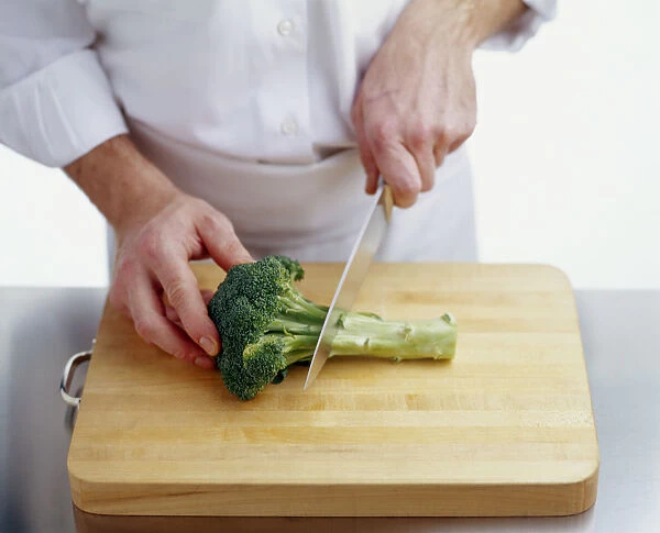 Using kitchen knife to cut stem from broccoli
