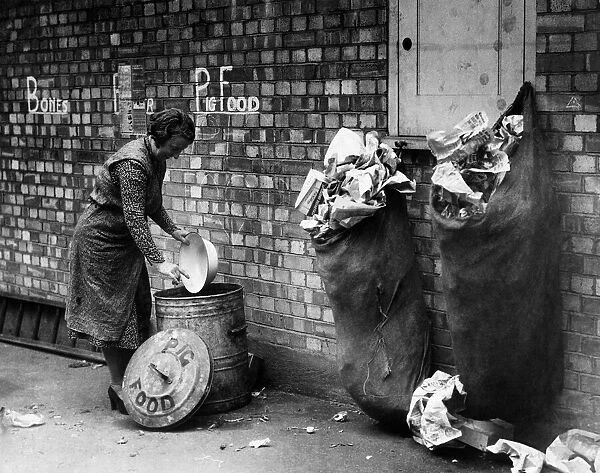 World War II: War on waste on the home front. A woman scrapes the remains of her dinner