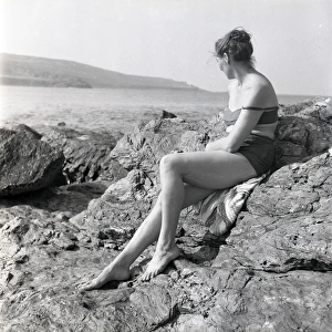 Woman sunbathing on the rocks in Cornwall