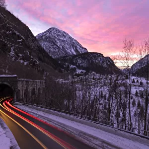 Car trail lights on the icy road at dawn, Campodolcino, Spluga valley, Sondrio province