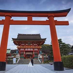 Japan, Kyoto, A wedding bride and groom pose at Fushimi Inari Shrine