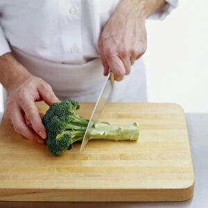 Using kitchen knife to cut stem from broccoli