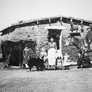 Pioneer family pose outside their sod house, Kansas, c. 1860 (b / w photo)