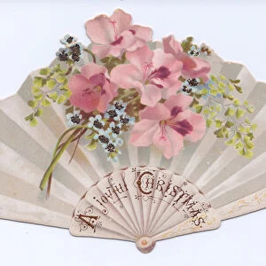 A Victorian die cut Christmas card in the shape of a fan with images of flowers