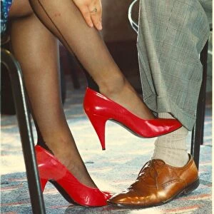 A woman touching a mans leg with her foot